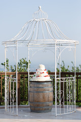 Wedding cake on an oak barrel in a gazebo