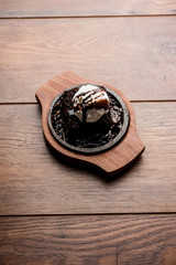 sizzling chocolate brownie is a sweet dish made using scoop of ice-cream on top served with a generous pouring of melted chocolate. server hot. selective focus