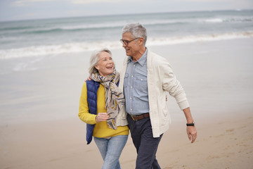  Happy senior couple walking together on the beach