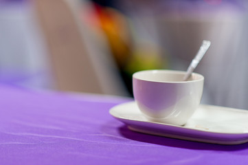 A white coffee mug is placed on a purple table. Coffee concept with copy space