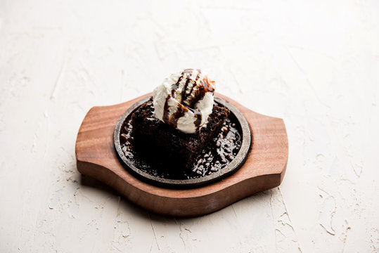 sizzling chocolate brownie is a sweet dish made using scoop of ice-cream on top served with a generous pouring of melted chocolate. server hot. selective focus