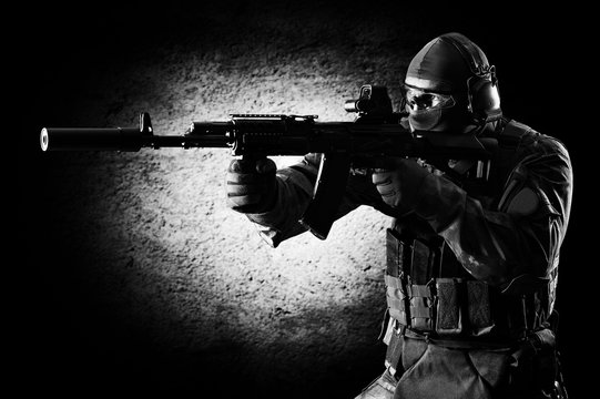 Special unit soldier stands with a gun in his hands and aims at the target.