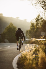 A side shot of a professional slim cyclist riding up a mountain