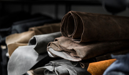 Different pieces of leather in a rolls. The pieces of the colored leathers. Rolls of natural brown and black and other leather. Raw materials for manufacture of bags, shoes, clothing and accessories.