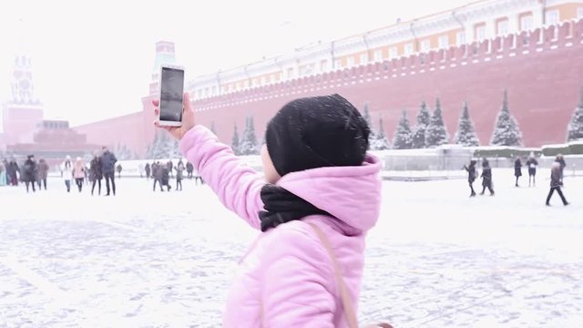 girl takes a selfie on red square in Moscow on a bright frosty winter day with snow