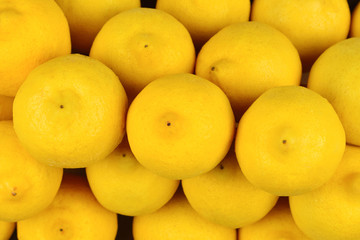 A lot of juicy colorful lemons in the box. Lemons background.