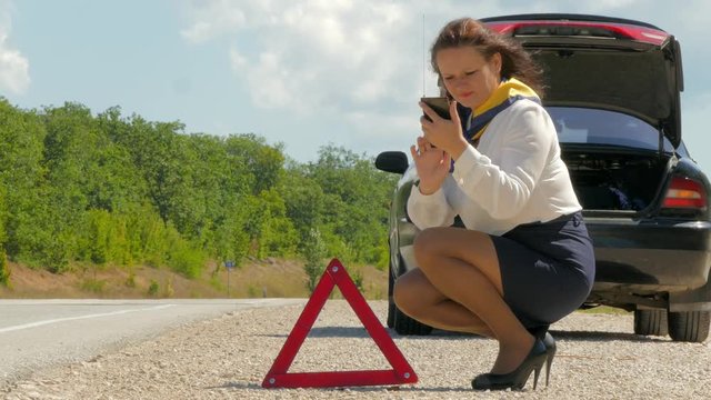 woman talking on the phone next to the warning triangle