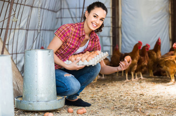 Portrait of young woman farmer holding fresh eggs in hands in henhouse © JackF