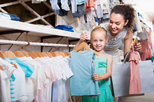 Woman with small daughter in kids apparel boutique