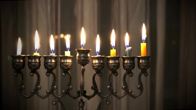Last eighth day of the Jewish holiday Hanukkah. Nine Hanukkah candles are burning on light curtain background. 4k