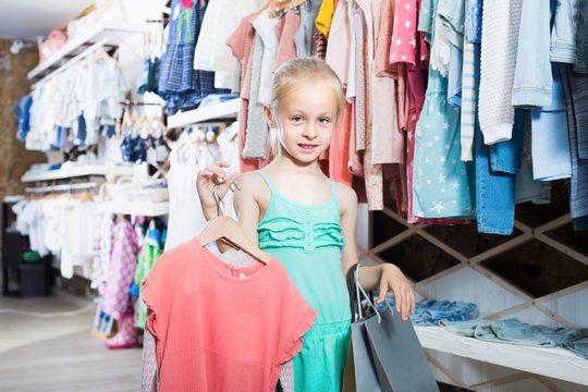 Girl holding shopping bags in children clothes boutique