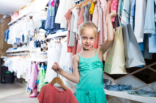 portrait of  girl standing in kids clothes store with shopping bags