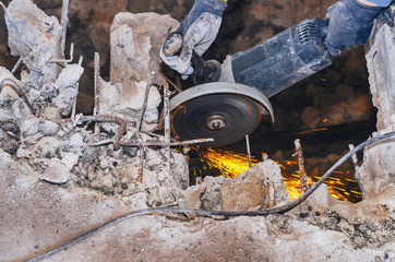 Male worker saws a disk grinding saw armature into a reinforced concrete panel, the destruction of...