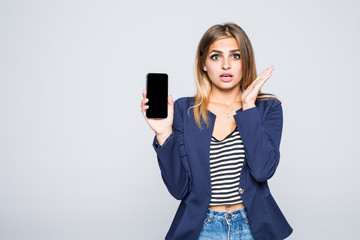 Naklejka premium Surprised happy brunette woman showing blank smartphone screen while looking at the camera with open mouth over white background