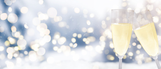 champagne glasses against festive blurry winter christmas background with circular bokeh lights