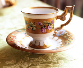 Fototapeta premium Romantic antique coffee cup with saucer in Biedermaier style, hand painted in gold and enamel with colorful flowers