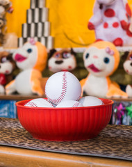 Close-up of baseball balls for the game of throw at jars in a fair. In the background the jars and the prize puppets.