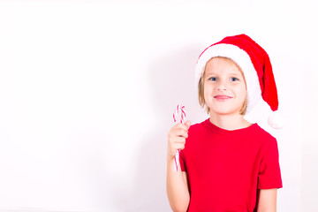 Happy boy in Santa red hat holding candy in hand. Christmas concept.