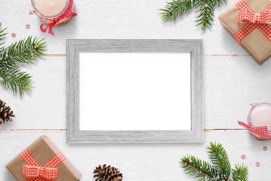 Horizontal photo frame surrounded with Christmas New Year gifts, tree branches and decorations. Isolated frame for photo mockup.