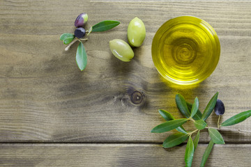 Bowl with apulian olive oil and olive branch on the wooden table with copy space, flat lay