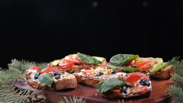 Nuts fall down on number of fresh sandwiches put on wooden background. Food serving concept. Christmas tree branches on board. Vegeterian concept. hd.