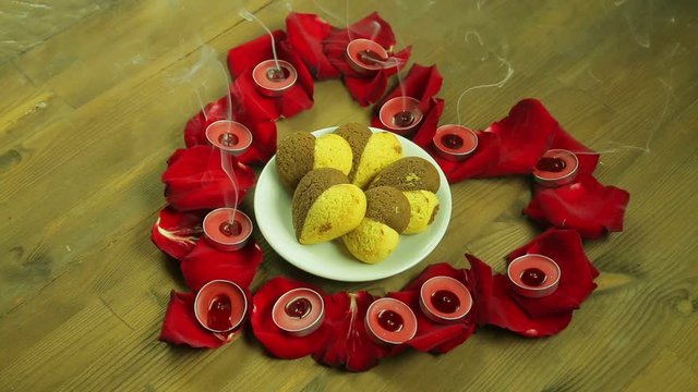 The girl blows out the candles on the heart of rose petals.