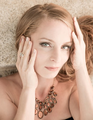 Obraz premium Closeup portrait of a beautiful woman lying and posing on the stairs and wearing a necklace on a sunny day.