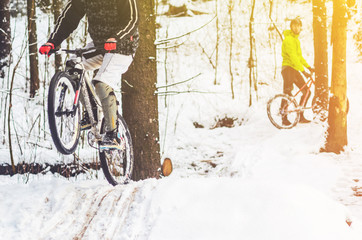 Bike rider flies through the air. Mountain biking on trails in a snowy forest. Extreme winter sport.