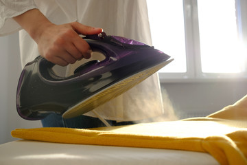 Girl ironing clothes  at home a yellow jacket