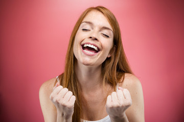 Euphoric young woman celebrating her successful over pink background.