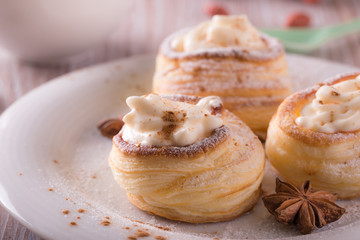 Sweet dessert from puff pastry filled by curd cheese on wooden board