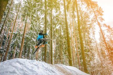 Silhouette of a cyclist in a jump. Mountain biking on trails in a snowy forest. Extreme winter sport. Bike rider flies through the air