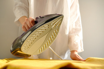 Girl ironing clothes  at home a yellow jacket