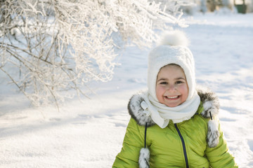 Fototapeta na wymiar Happy little girl in bright winter clothes having fun in the snow