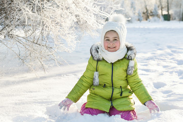 Happy little girl in bright winter clothes having fun in the snow