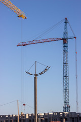 Construction site with a crane. The construction of residential, multi-family homes. Several cranes working on construction complex on the blue sky background