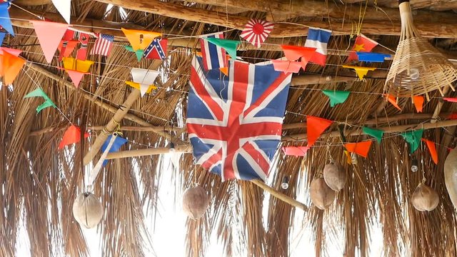 Decorative national flags of different countries hanging on strings in wooden tropical bungalow. Exotic rasta bar interior. Summer beach house on Koh Phangan island, Thailand.