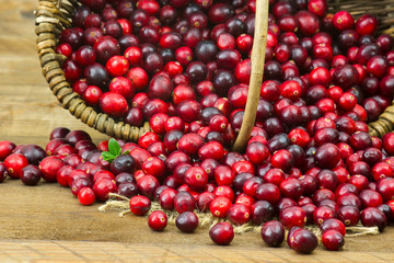 Cranberries in a basket on wooden background.