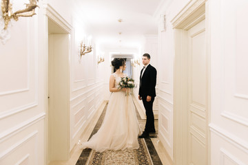 The first meeting of the bride and groom in the bright corridor of a luxury hotel. Wedding day