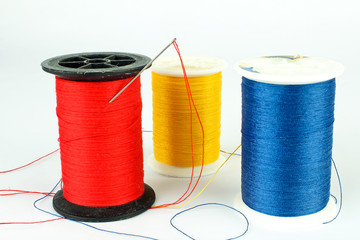 Spools of Thread - red yellow blue with Needle on White Background