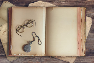Old  book with vintage glasses and pocket watch