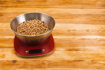 Checkpea in bowl on an electronic scale on a natural wood background with copy space