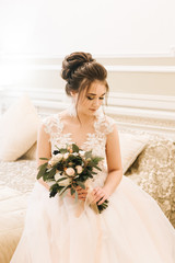 Portrait of an attractive young bride with a winter bouquet. Morning bride in a luxury hotel