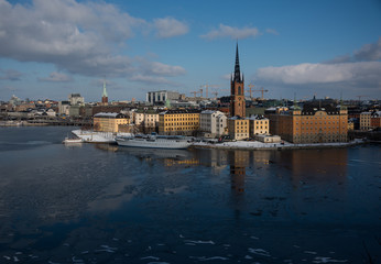Fototapeta na wymiar Winter view of Stockholm a frozen lake Mälaren and snow over the Town City Hall and the island Riddarholmen 