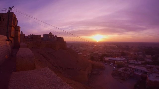 Ancient fort on hill and small desert town on valley in rays of sunrise