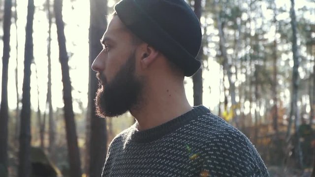 Bearded man in the forest looking far ahead. Brutal unshaven guy in the forest.