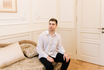 Morning of the groom. Groom morning preparation. Young and handsome groom getting dressed in a wedding shirt