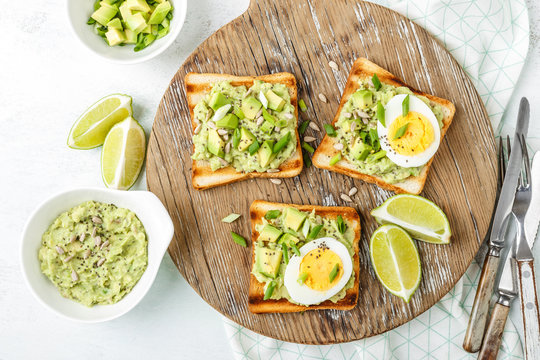 avocado toasts, healthy snack of grilled bread with guacamole slices avocado, boiled eggs, chia seeds and green onions