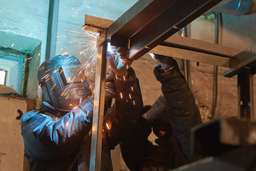 welder welds a metal frame for the power plant.