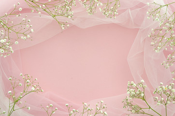 Flat lay wedding concept. Frame made of gypsophila and white tulle on pink background with copy...